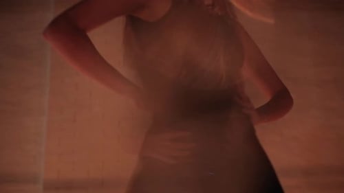 Junge schöne Frau im schwarzen Kleid tanzt im Studio mit Kerzenlicht