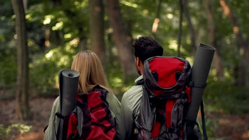 Couple With Backpacks in Forest Enjoying Outdoors Together on a Sunny Day
