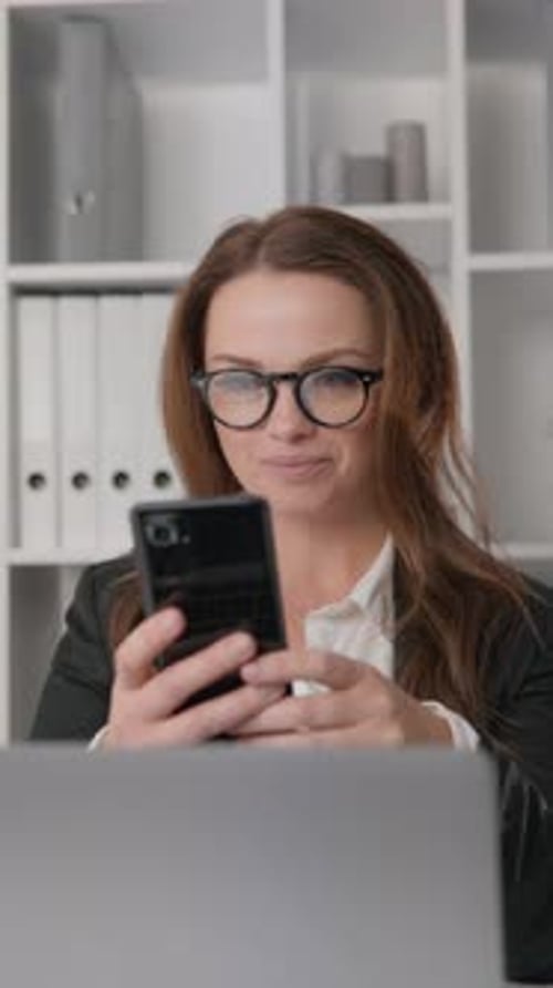 Energetic Businesswoman Focused on Computer in Office Environment on Phone Planning Strategic Moves