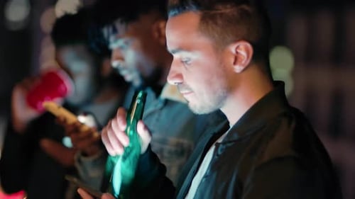 Noite, cerveja e amigos relaxam em um telhado, checando o telefone e planejando diversão em uma cidade