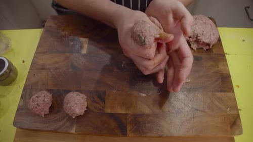 Close up on chef hands forming meat balls and lay them on top of wooden cut board. Slow motion.