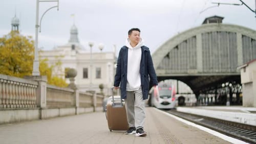 Man asian passenger arrives or departure by train home in town, with big suitcase, tourist