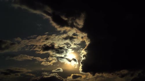 The sun sets behind a black cloud