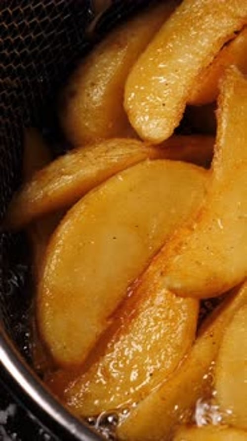 Cooking Potatoes Wedges in Deep Fryer Closeup Vertical
