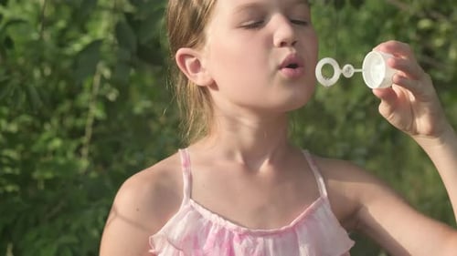 Kid Girl Playing with Blowing Soap Bubble in Garden Summer Day