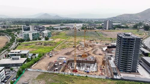 Zumbido aéreo orbitante de una obra en construcción con grúas amarillas, trabajos de cimentación, torres de gran altura,