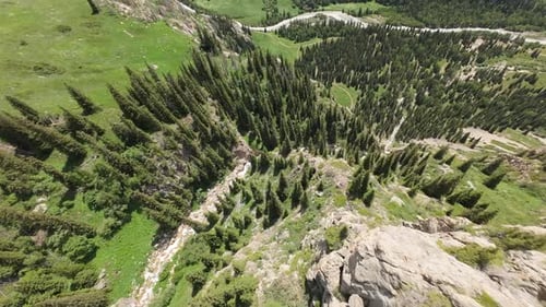 Waterfall Cascading Down Rocky Mountainside in Green Valley
