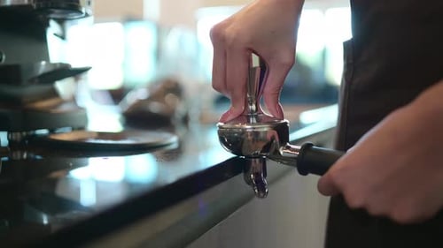 Barista Tamping Coffee Grounds in Portafilter Close Up