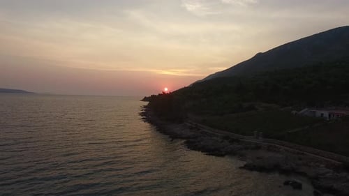 Ascending aerial view of sunset on the coast of Croatia. Beautiful purple sky over gentle waves on t