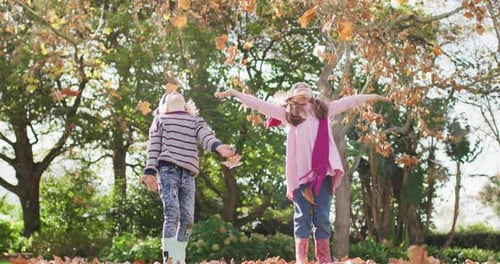 Video of happy caucasian brother and sister having fun throwing autumn leaves in garden