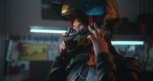 Young Woman Puts on Black Helmet With Green RIDE Graphics Fastens Chin Strap Lowers Visor