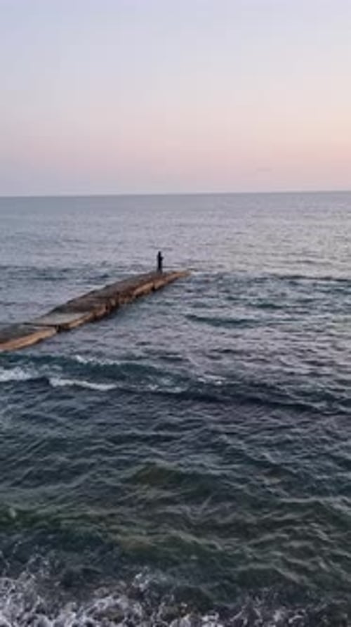 Silhouette masculine tenant une canne à pêche en soirée Une vue de la silhouette de l'homme Restez sur la petite jetée et maintenez