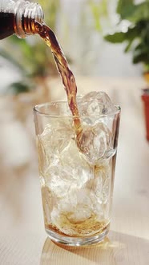 Pouring Soda into Ice Filled Glass Indoors