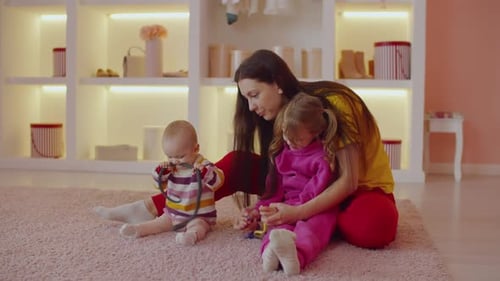 Mother with Children Playing on Pink Rug Indoors