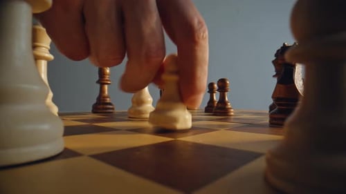 Person Shifting Pawn Figure on Checkered Platform Between Opposing Units Closeup