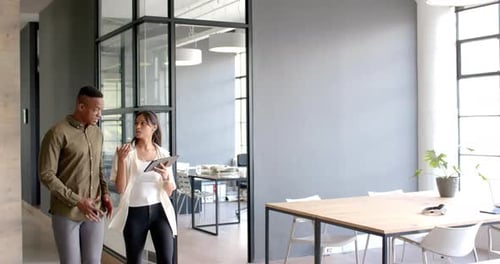Discussing business strategy, colleagues walking in modern office holding tablet