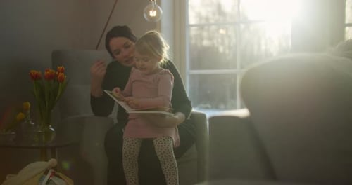 Beautiful toddler girl reading with loving mother, close portrait