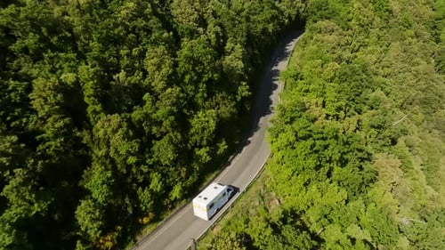 Aerial view folllowing a camper van driving on a dangerous, high altitude road