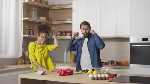 Pareja casada bailando y divirtiéndose mientras cocinan