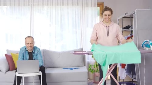 Woman Irons Shirt at Home, Man Approves
