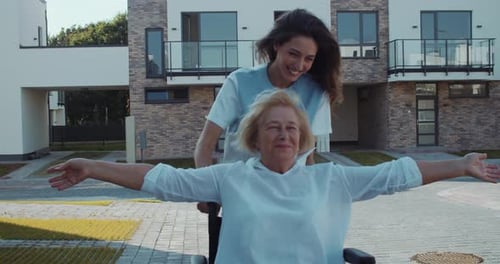 Senior Woman Enjoying Wheelchair Ride with Young Caregiver