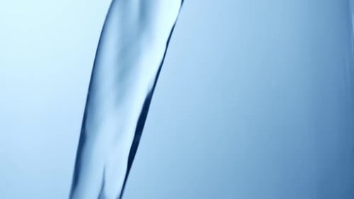Clear Water Pouring on Blue Background Close Up