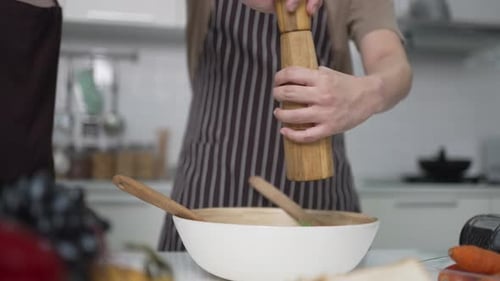Seasoning Salad with Pepper in Bright Kitchen