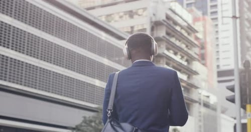 Fun businessman enjoying listening to music and walking in modern corporate business area
