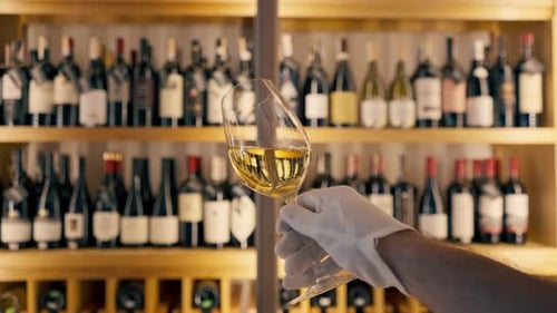Gros plan d'un verre de vin tenu par un sommelier dans un restaurant italien