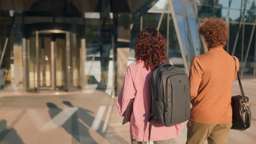 Rear View of Two Young Students Walking Casually to Modern University Campus