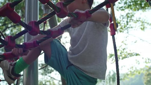 As Evening Falls In Golden Light, Boy Enjoys Climbing Toy At The Park
