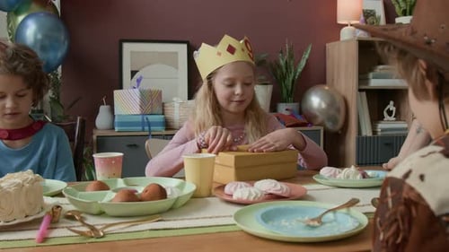 Excited Girl Opens Birthday Gift at Party with Friends