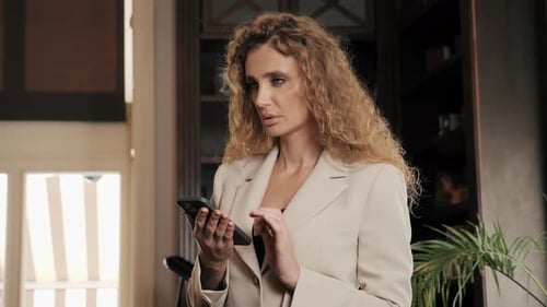 Concentrated Businesswoman Looking Working with Mobile Phone in Hotel Lobby
