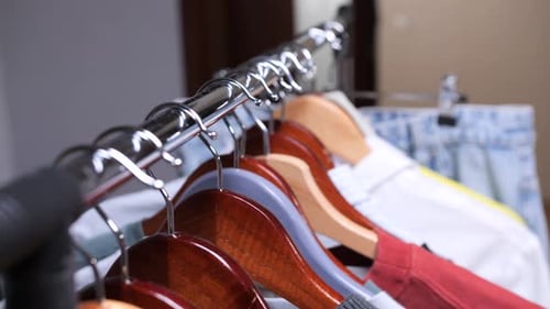 Rack of Clothes on Wooden Hangers in Room