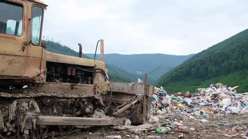 Dilapidated Tractor at Landfill with Mountain Backdrop