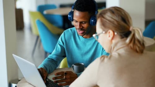 Une femme et un homme discutent d'un projet collaboratif en ligne sur leur lieu de travail