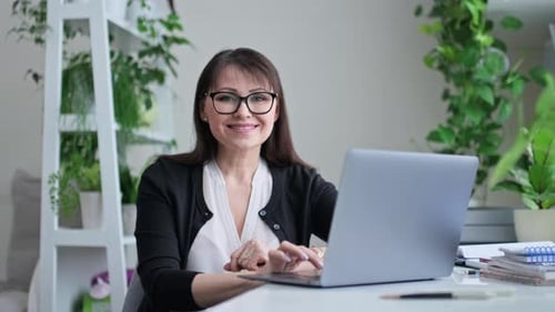 Portrait of Smiling Mature Woman Looking at Camera While Sitting at Workplace in Office
