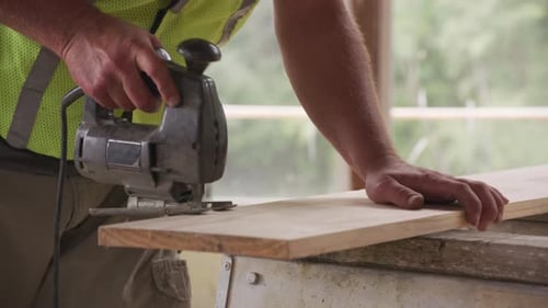 Man Cutting Wood with Jigsaw, Working on Construction
