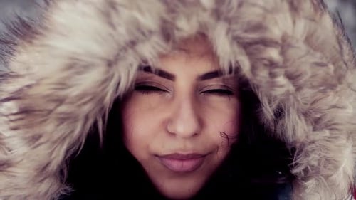 Young woman stands in snowy winter wonderland forest landscape portrait