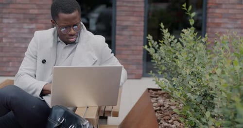 Successful African American Businessman Using Laptop Computer Typing Working Online Outdoors in City