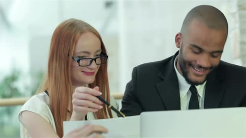 Smiling Successful Businessmen Sitting at Table in Office While Discussing
