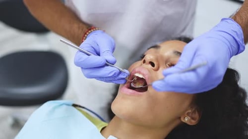 Closeup of a unrecognisable dentist in mask and gloves wearing an examination mirror checking