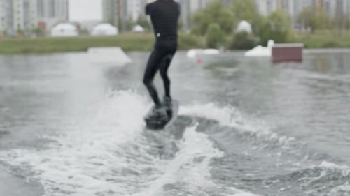 Man Riding Wakeboard across Lake