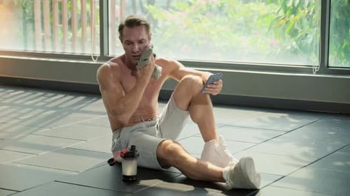 Man Using Phone After Gym Drinking Water