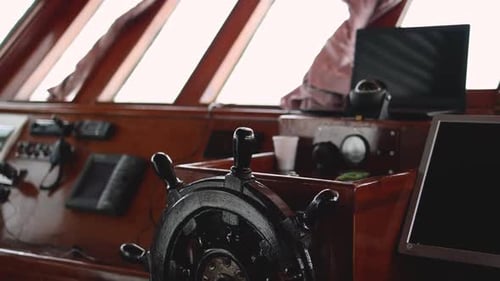 Medium pan across captains helm steering wheel, navigation center in classic boat
