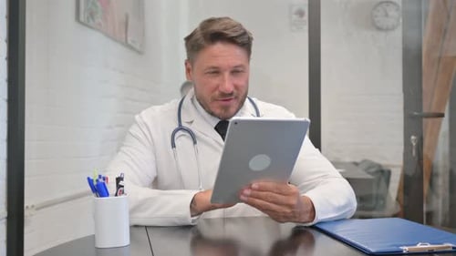 Doctor Using Tablet at Desk in Office
