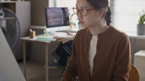 Asian Manager Doing Report on Computer at Office Desk