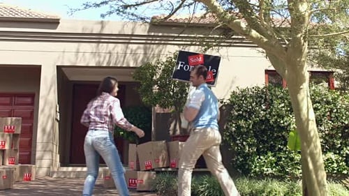 Cheerful couple removes sold sign and enters new home together celebrating