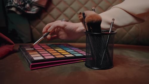 Nahaufnahme Palette mit Lidschatten und Make-up-Pinseln zum Auftragen von Make-up in Zeitlupe