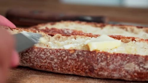 Close-up caucasian hand spreads margarine on fresh bread with butter knife